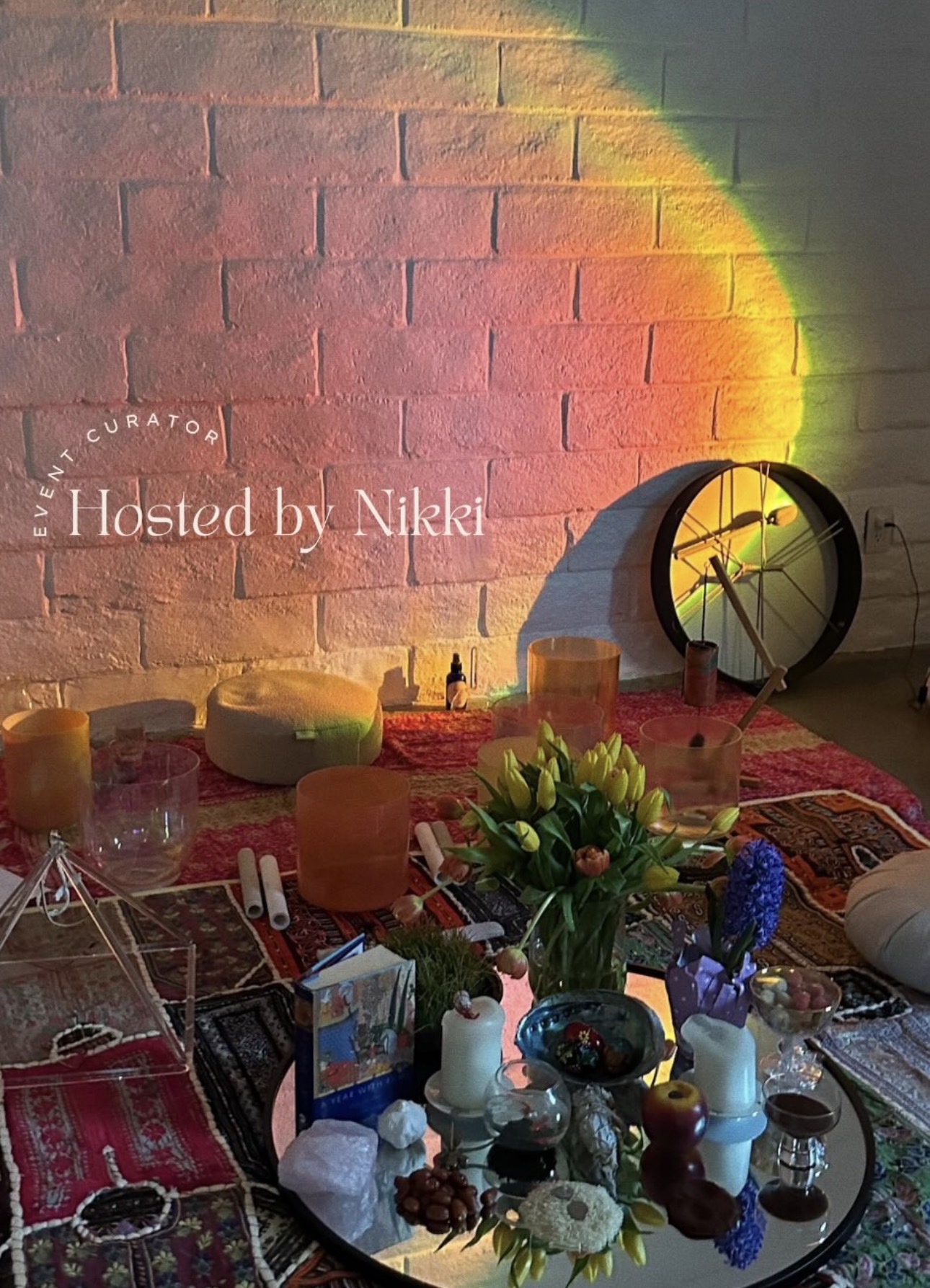 Party table with flowers, candles, and decorations against a brick wall with colorful light projection.