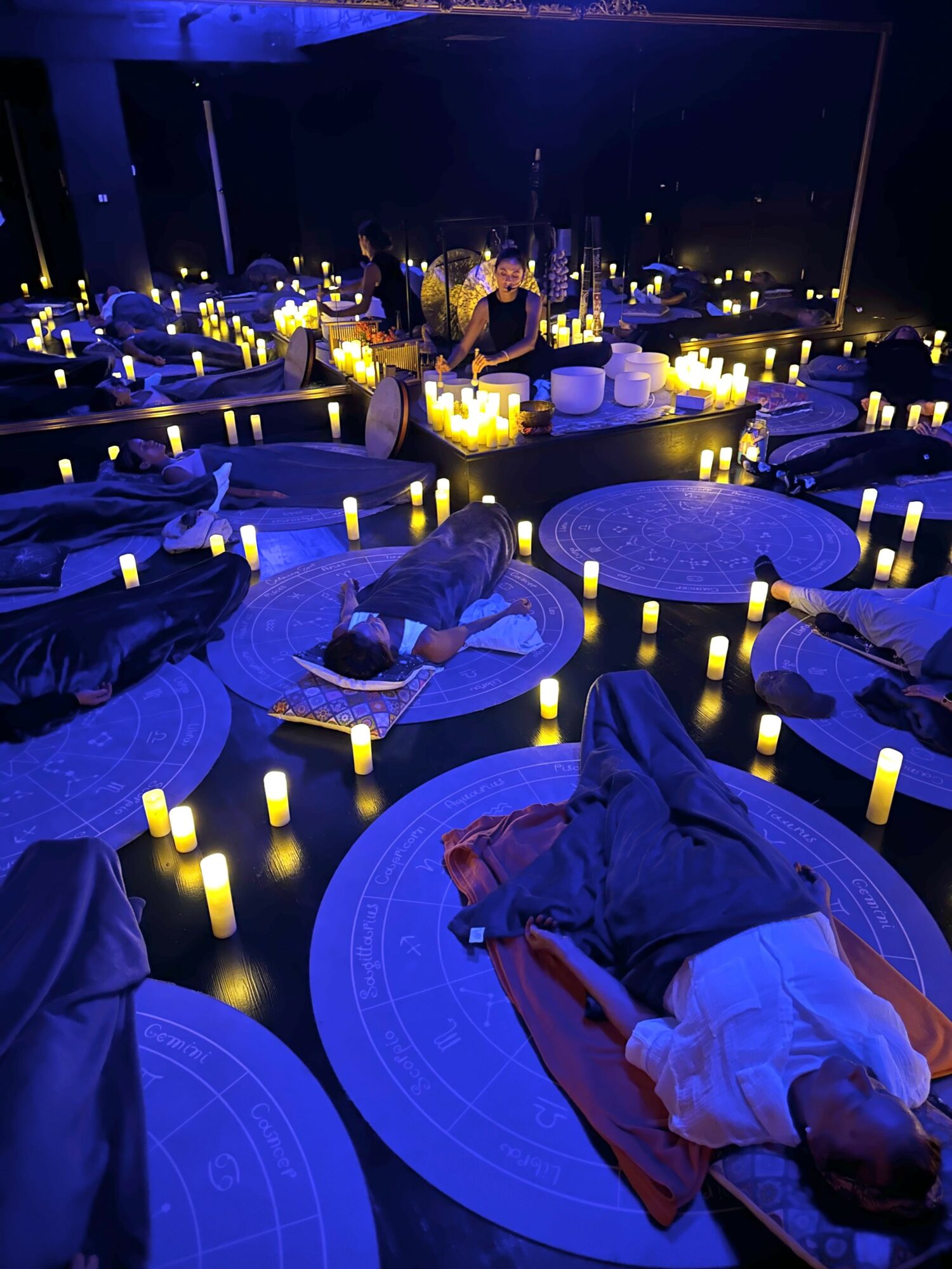People dining at tables with glowing candles on a dark outdoor terrace at night.