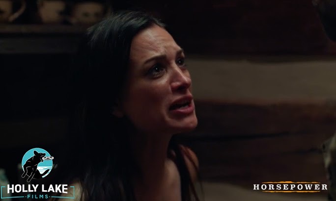 Woman with dark hair appears distressed, in a dimly lit room, with text and logos at the bottom.