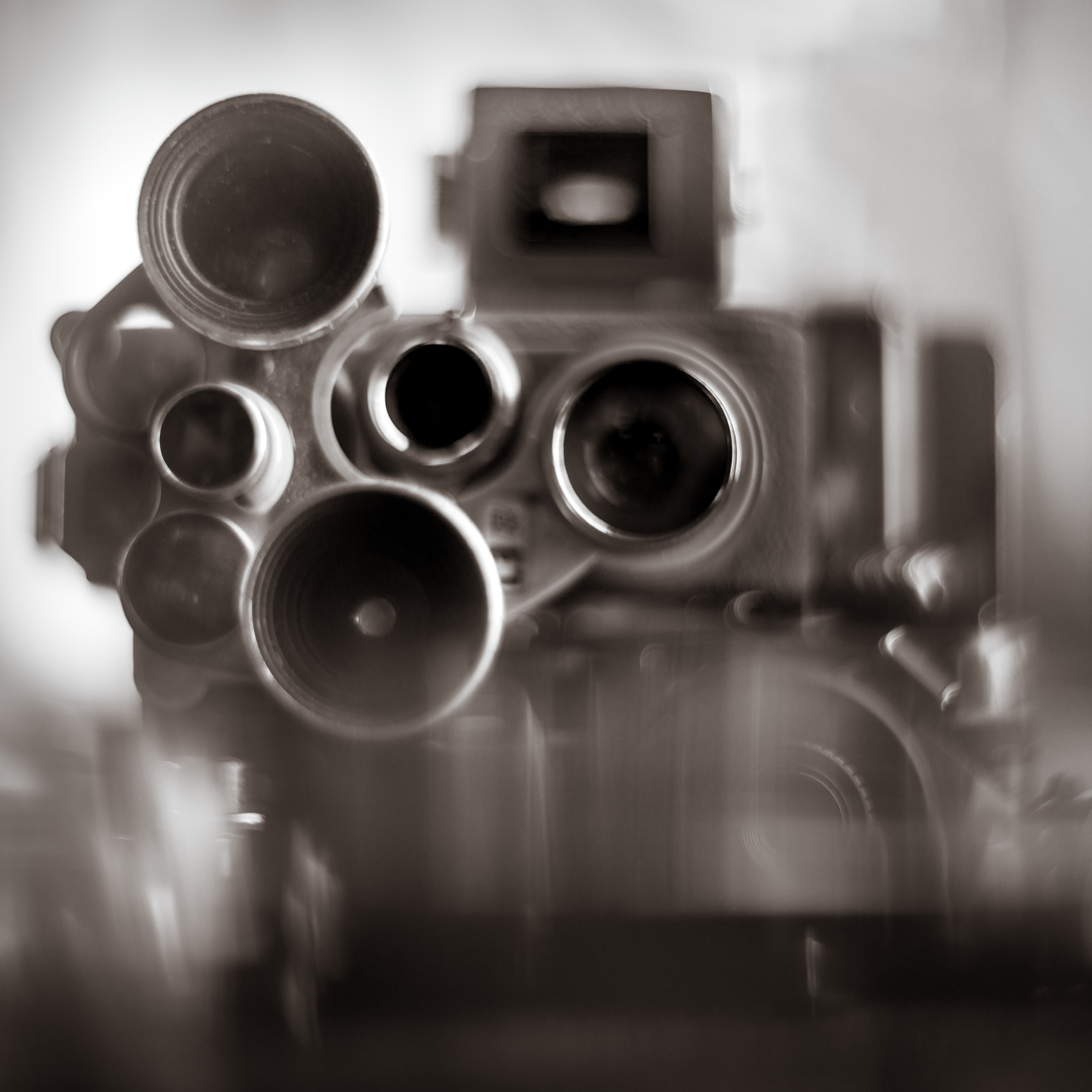 View of multiple gun barrels pointing towards the camera, with a blurred background and foreground, in black and white.