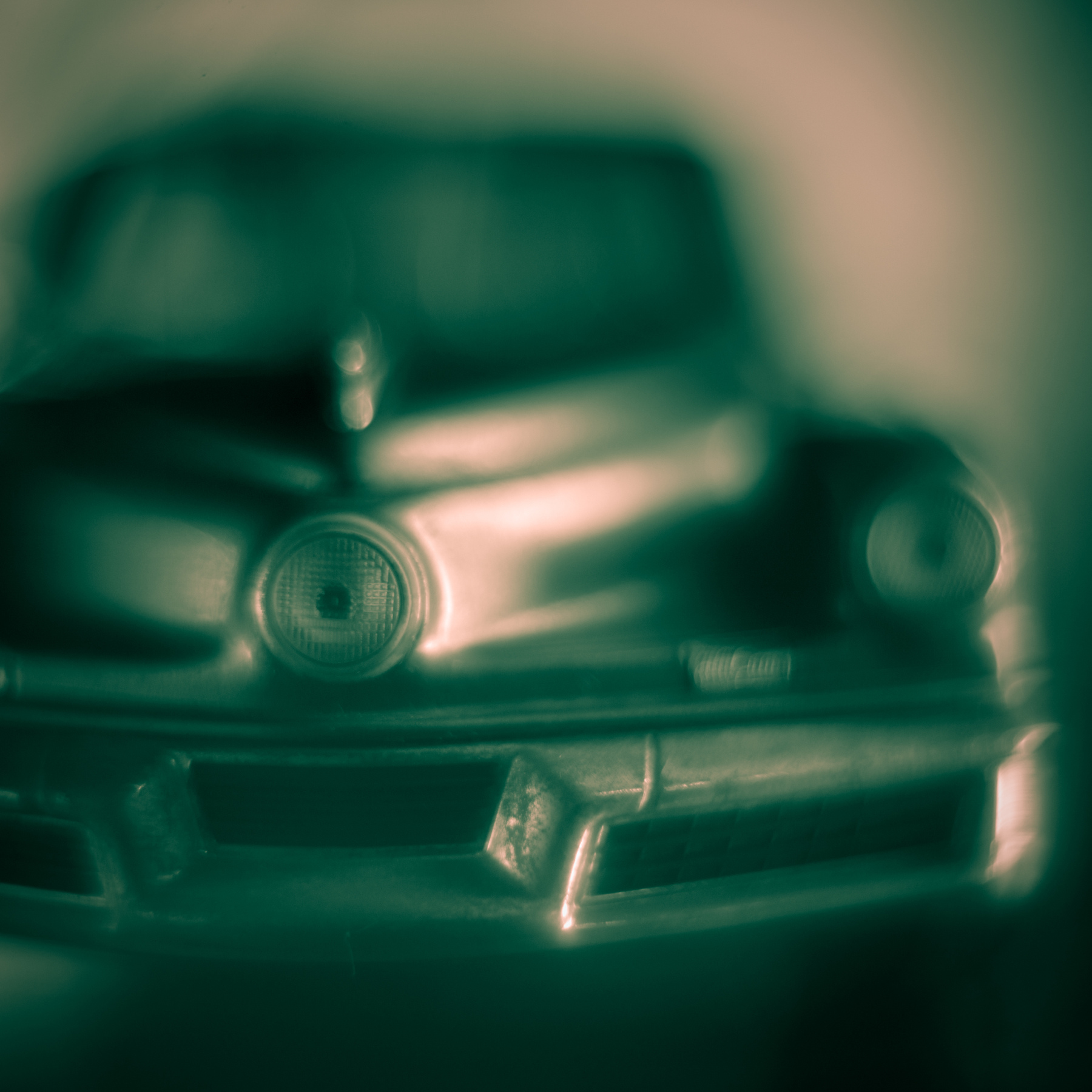 Blurred front view of a vintage car with round headlights and a prominent grille.