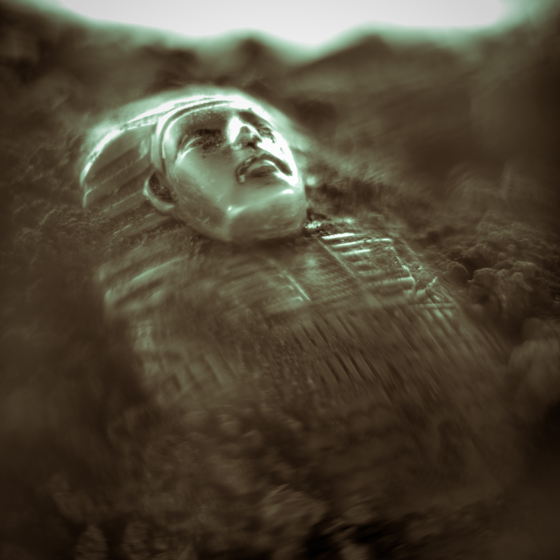 Person wearing a helmet lying in dirt, looking upward with a concerned expression, surrounded by dust or smoke.