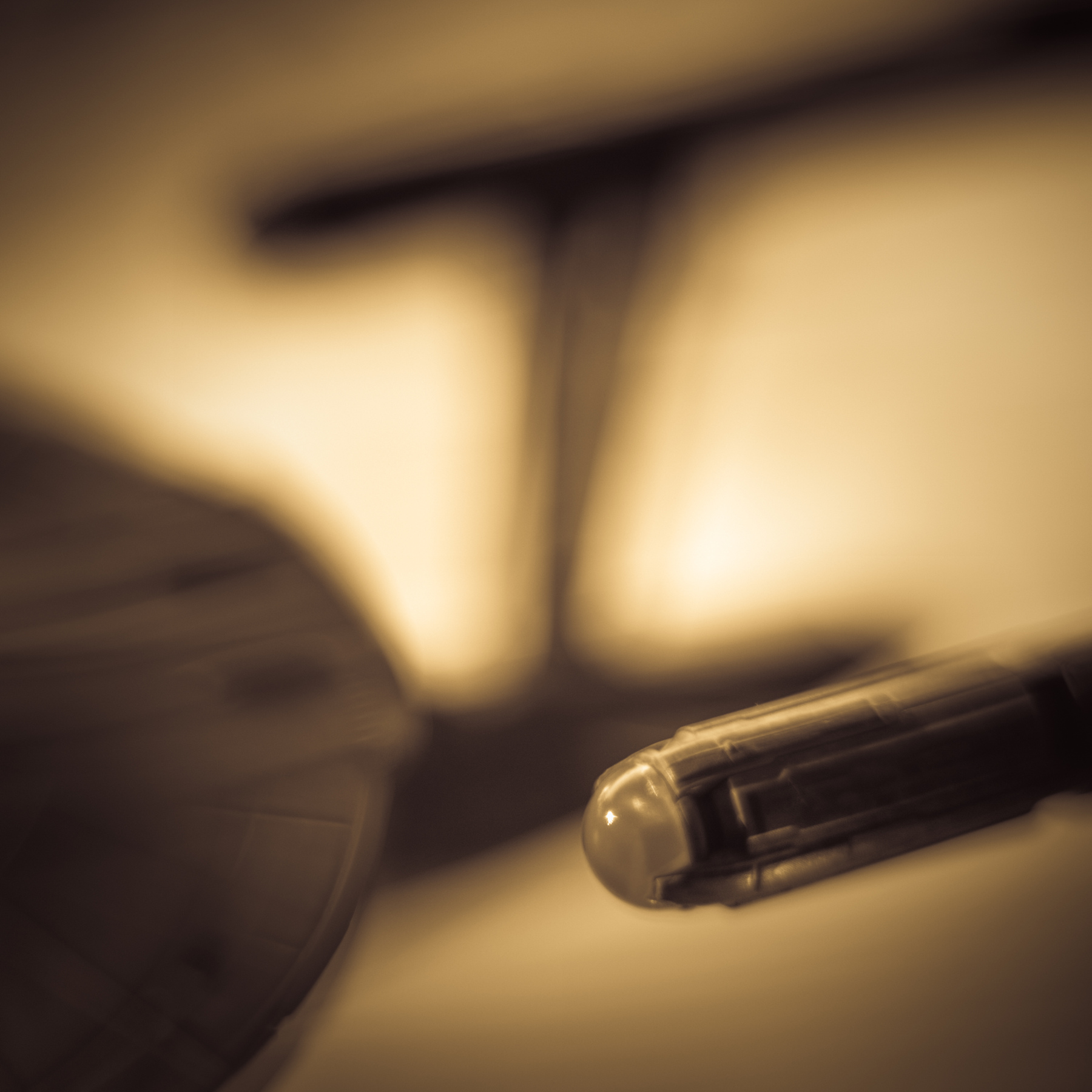 Close-up of a pen tip with blurred background, warm lighting, and soft focus.
