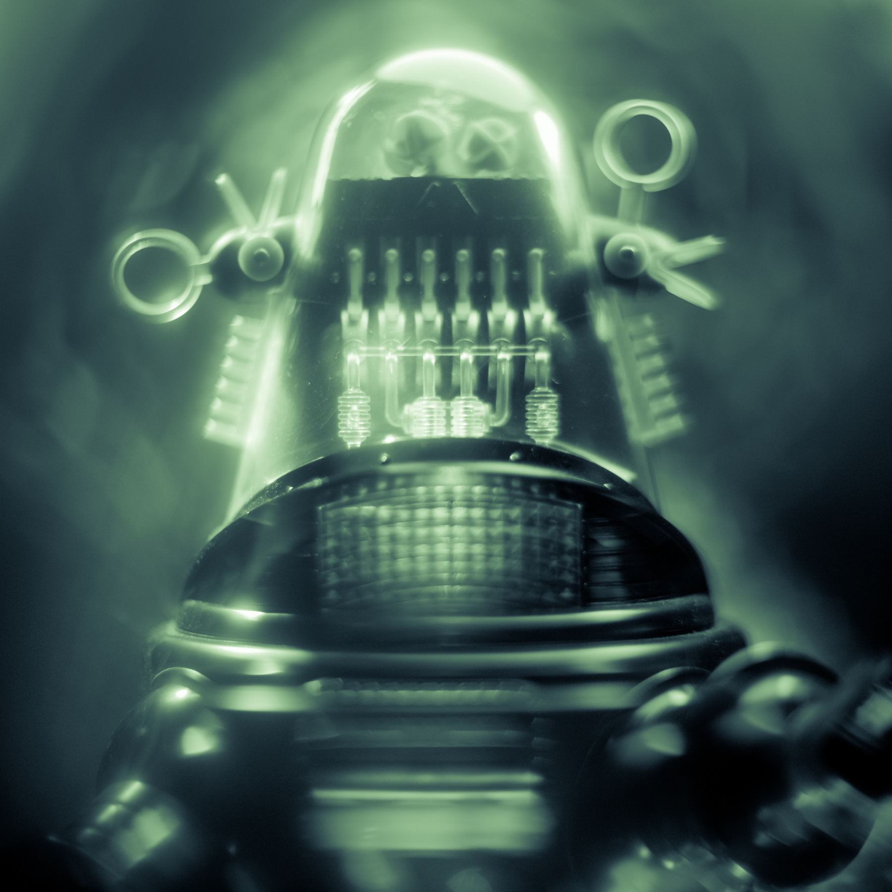 Close-up of a vintage robot with glowing green lights and mechanical details, set against a dark background.
