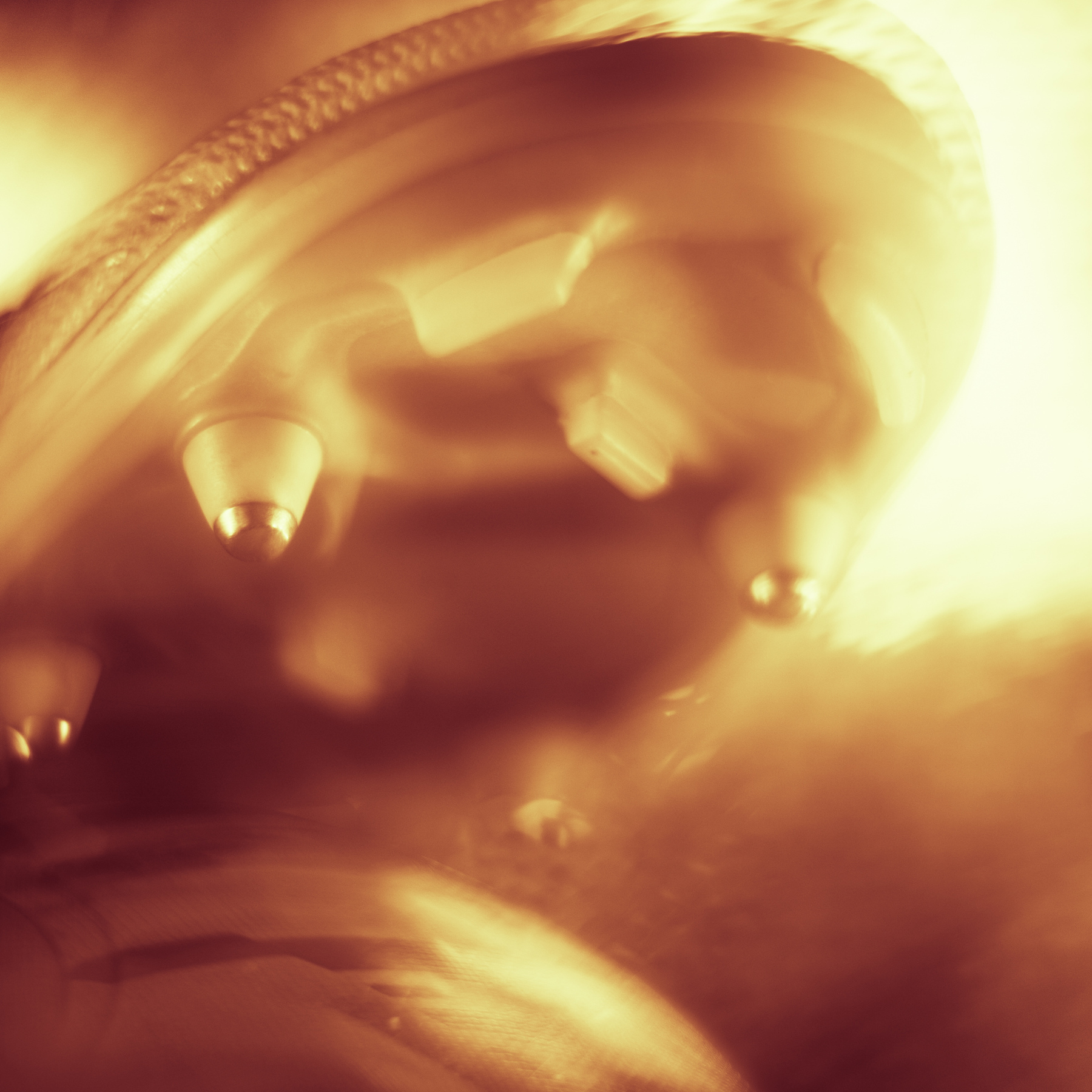 Close-up of a metallic object with blurred motion and warm lighting, possibly a musical instrument or machinery component.