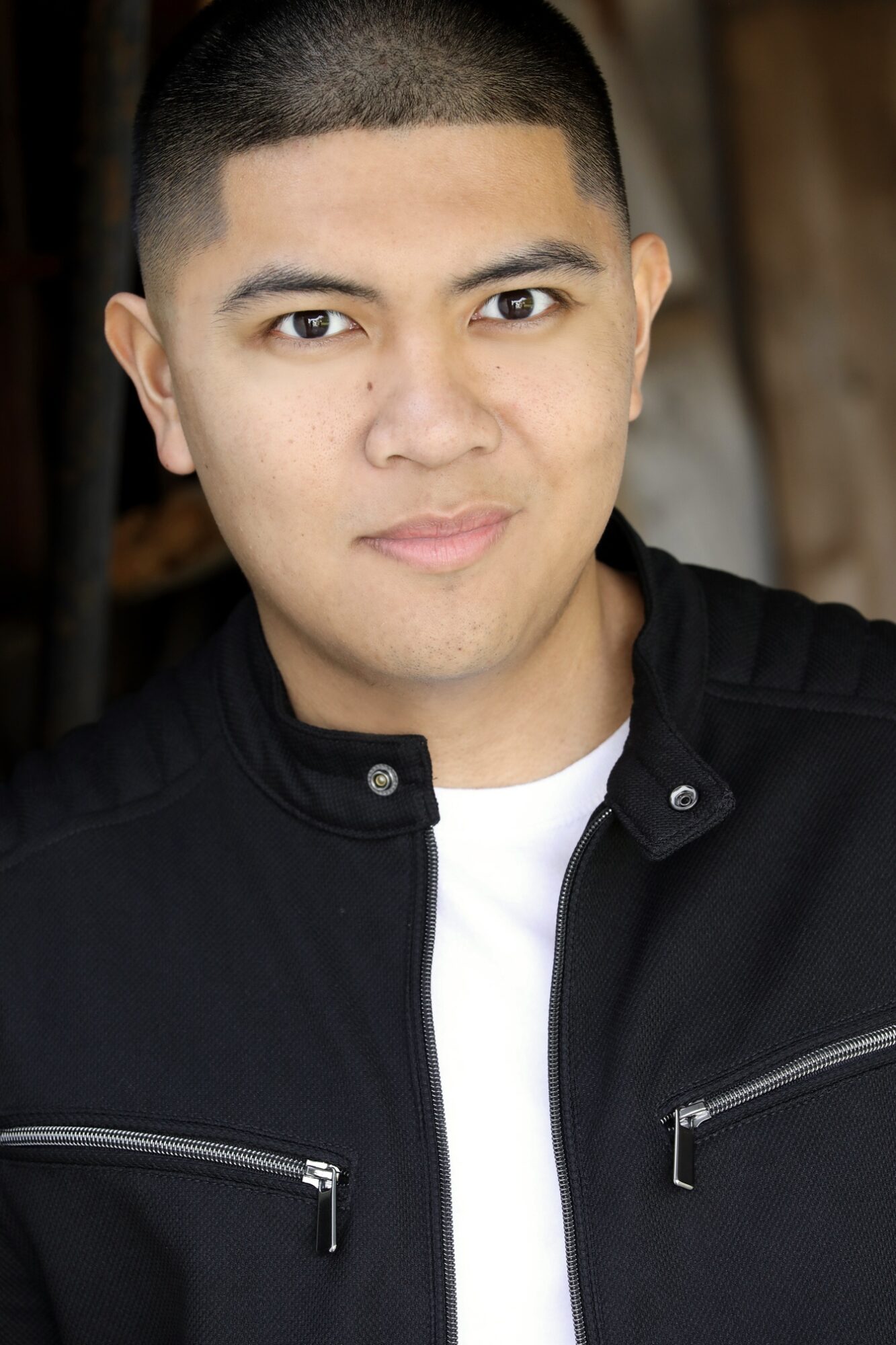 Young man with short hair wearing a black jacket and white shirt, looking at the camera.