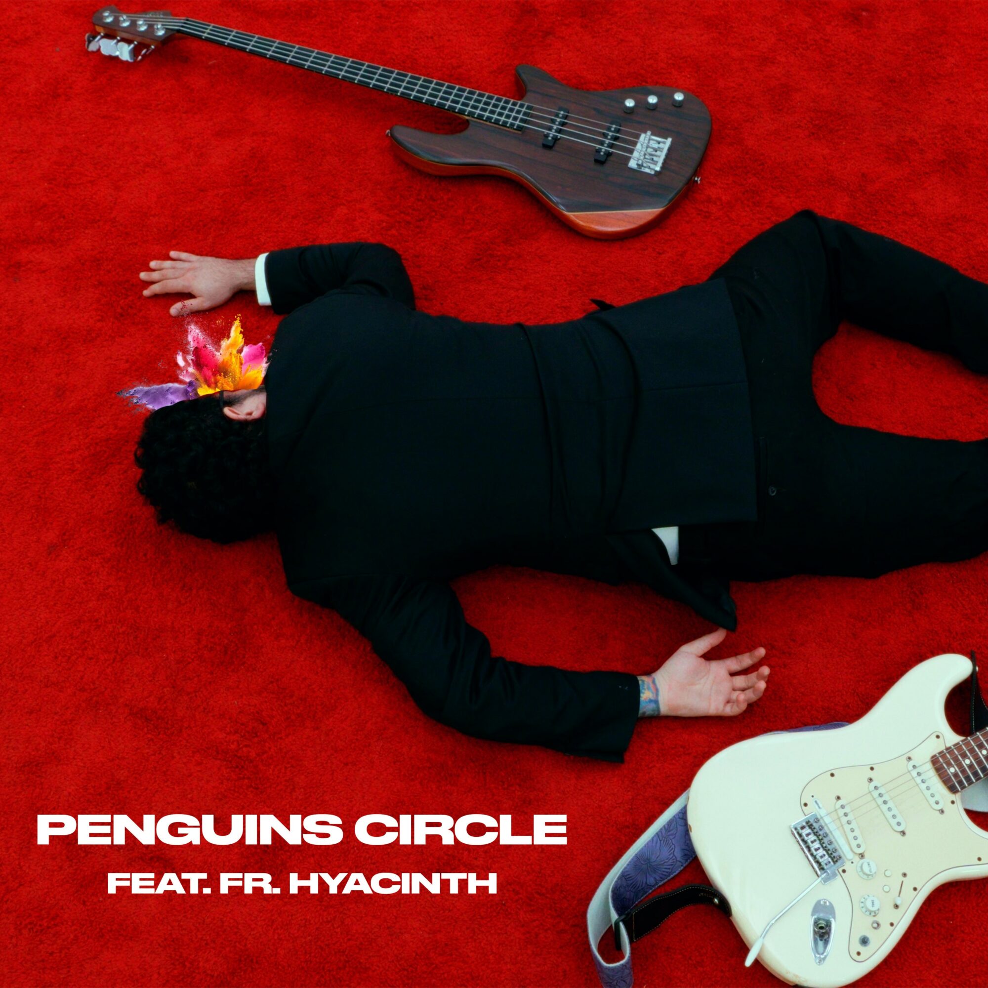 Person lying on red carpet with two guitars, one black and one white, and colorful objects near head.
