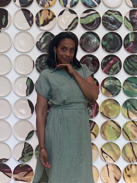 Woman in a green dress lying on a patterned floor with circular designs, looking at the camera.