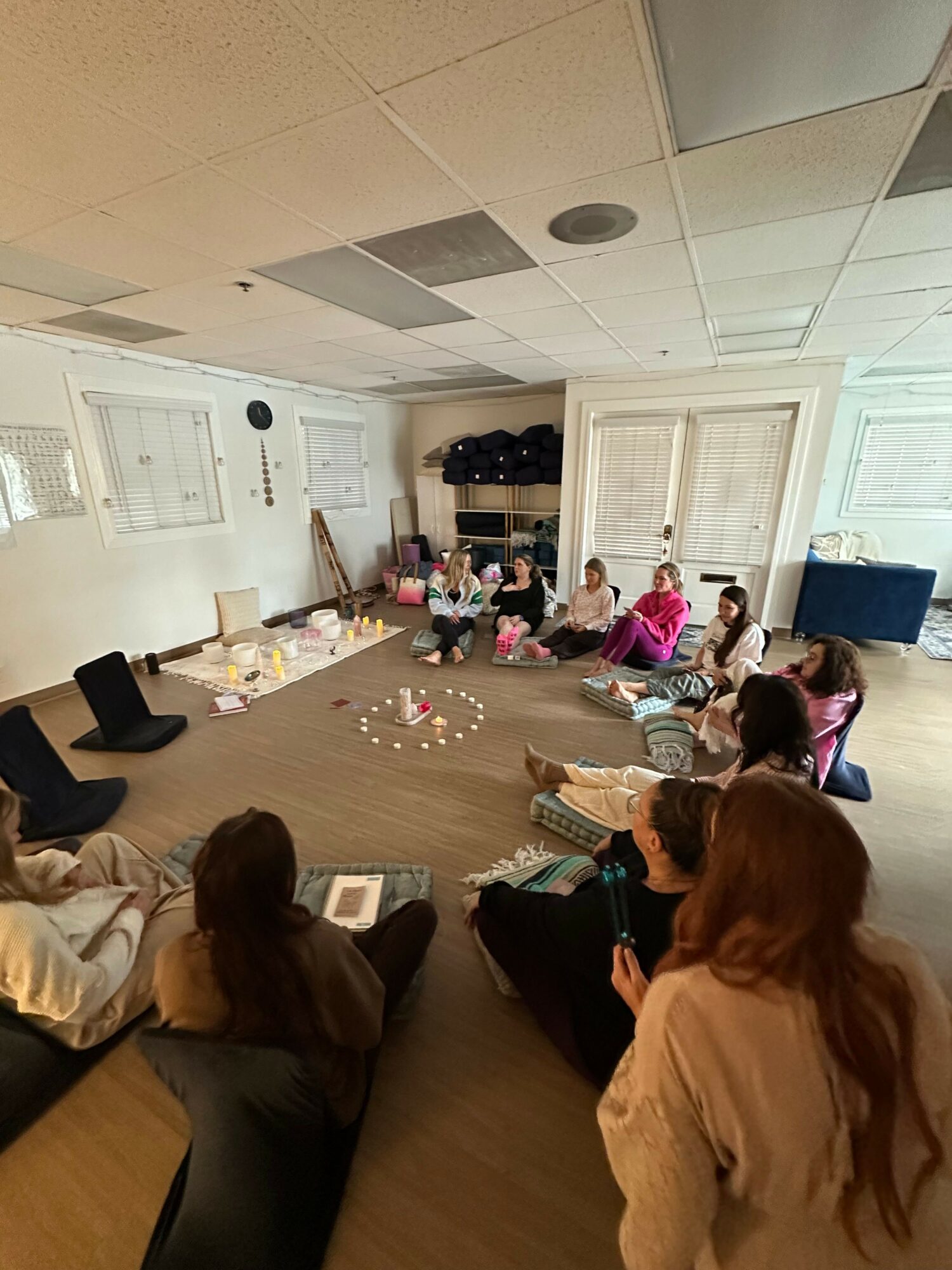 People gathered around a table with gifts and decorations in a room with tiled ceiling and white walls.