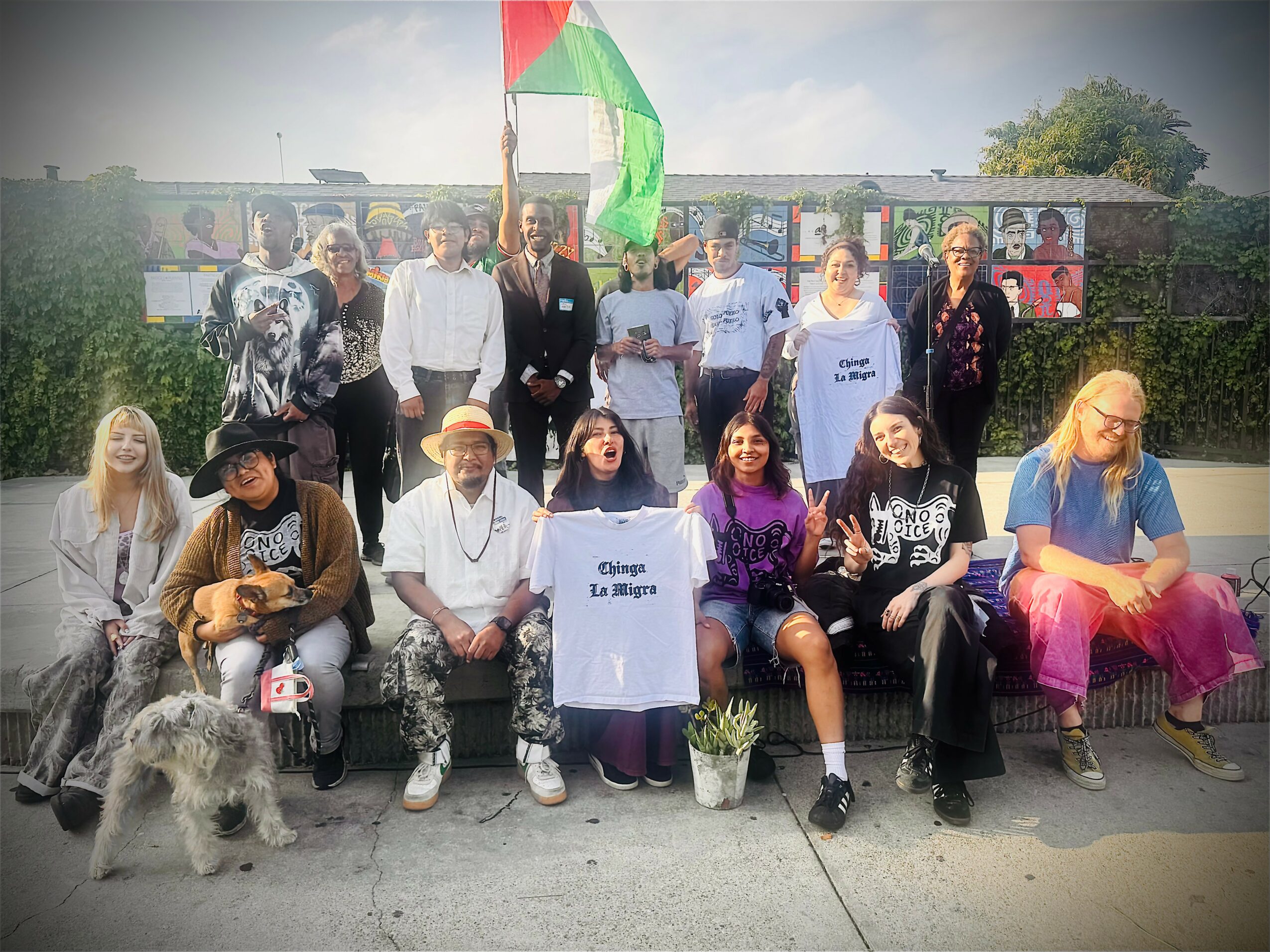 Group of people outdoors, some holding a flag, with a dog in front, and a sign that reads 'Gaza La Blaga'.