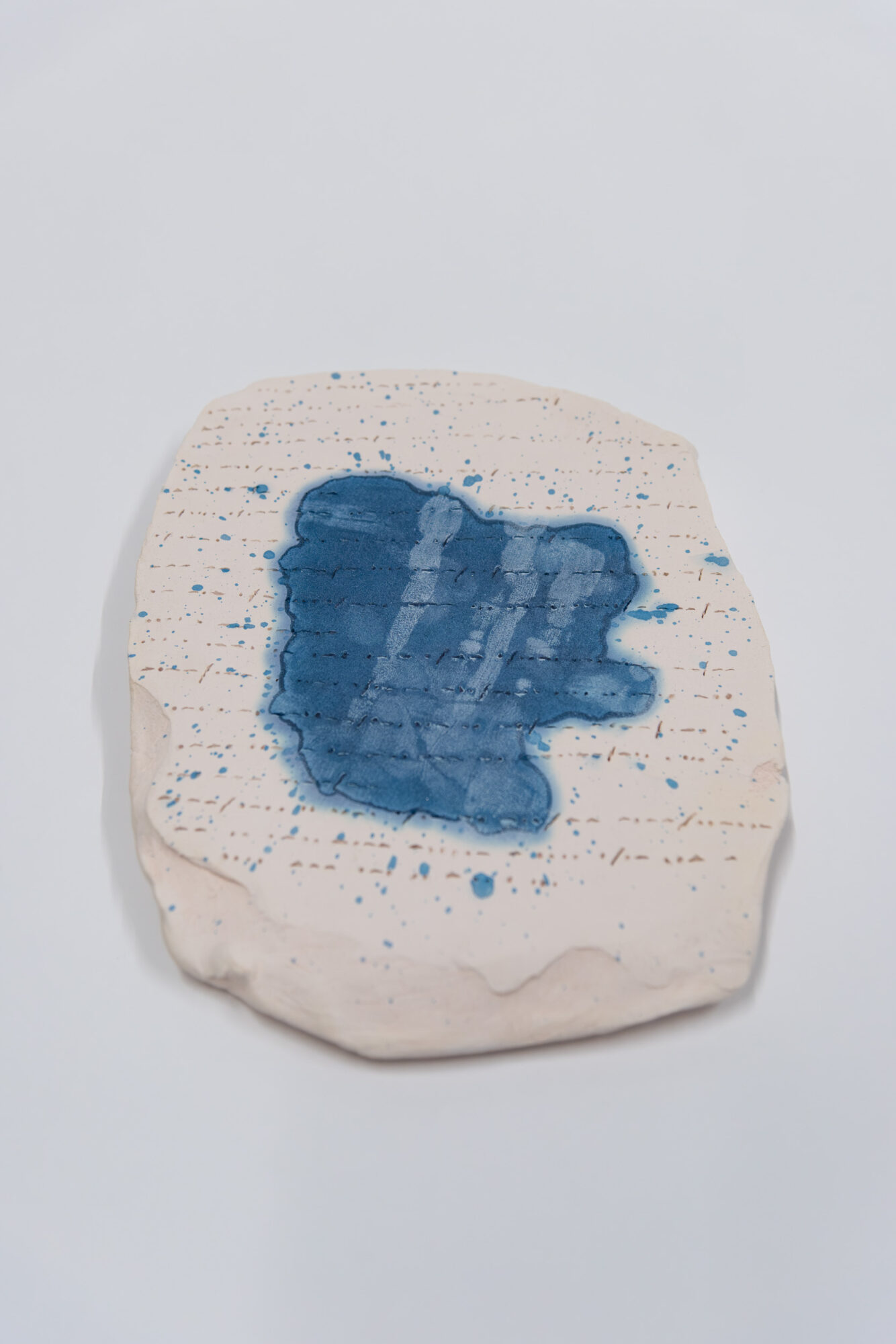 A piece of paper with blue ink blot and handwritten notes, on a white background.