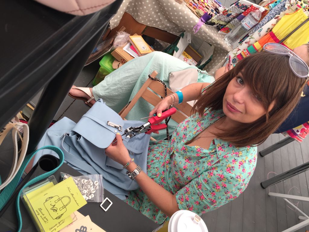 Woman with brown hair and glasses, wearing a floral shirt, shopping in a store with colorful items around her.