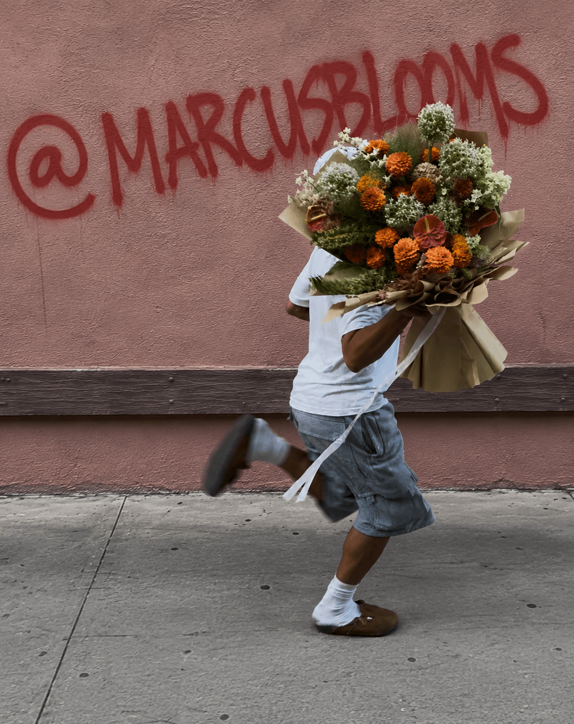 Child running with a large bouquet of flowers in front of a pink wall with red graffiti '@MARCUBLOOMS'.