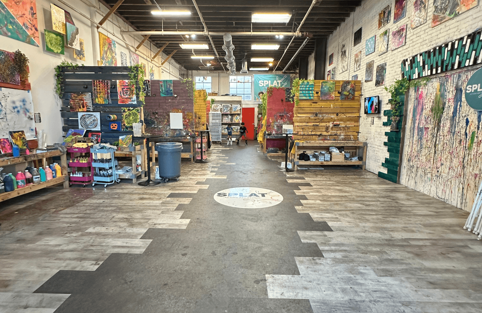 Interior of a colorful craft or art store with shelves, displays, and artwork on walls, viewed from the entrance.