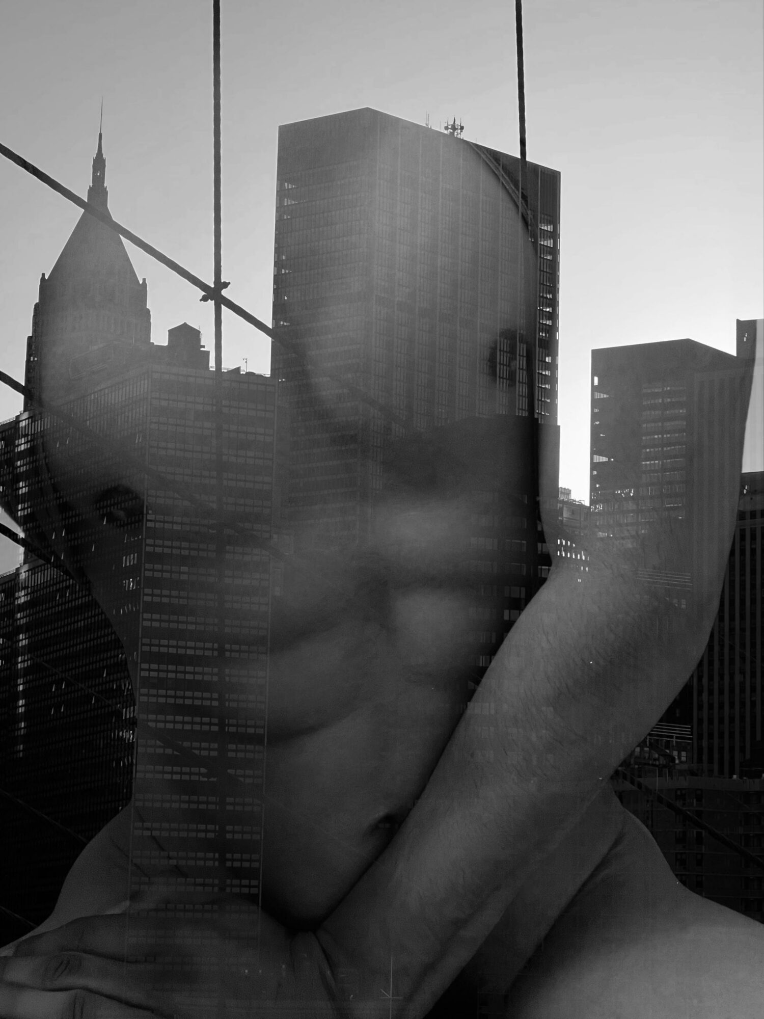 City skyline with tall buildings and a reflection of a person's face and hand on glass window.