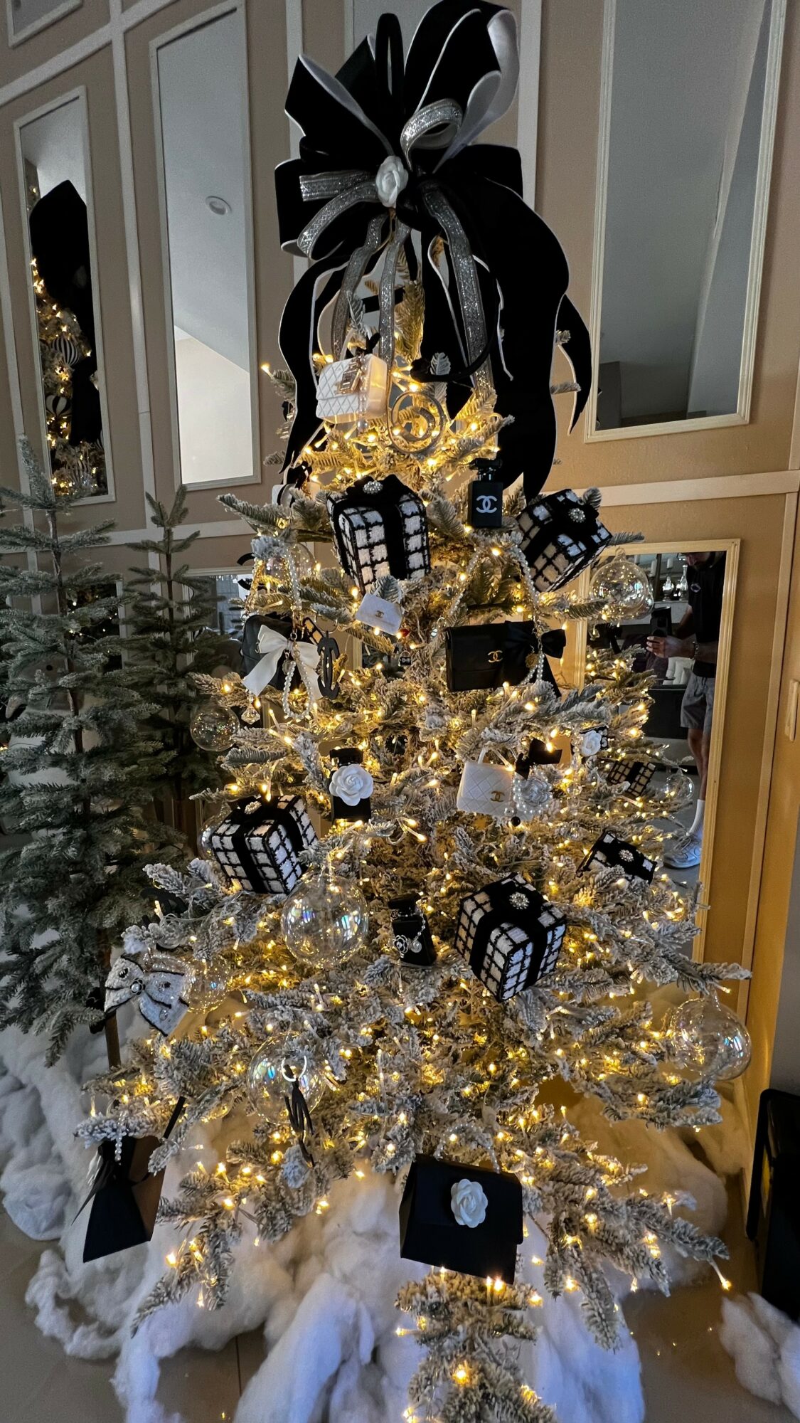 Decorated Christmas tree with black and gold ornaments, wrapped presents, and a large black and white bow on top.