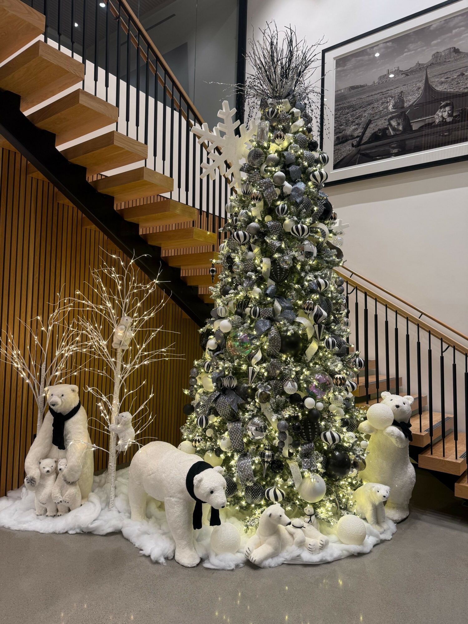 Floral arrangement with white and purple flowers, greenery, and decorative elements on a white fabric base, in an indoor setting.
