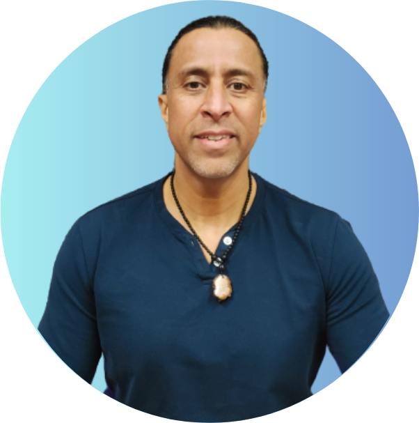 Man with long hair tied back, wearing a dark blue shirt and necklace, smiling against a blue gradient background.
