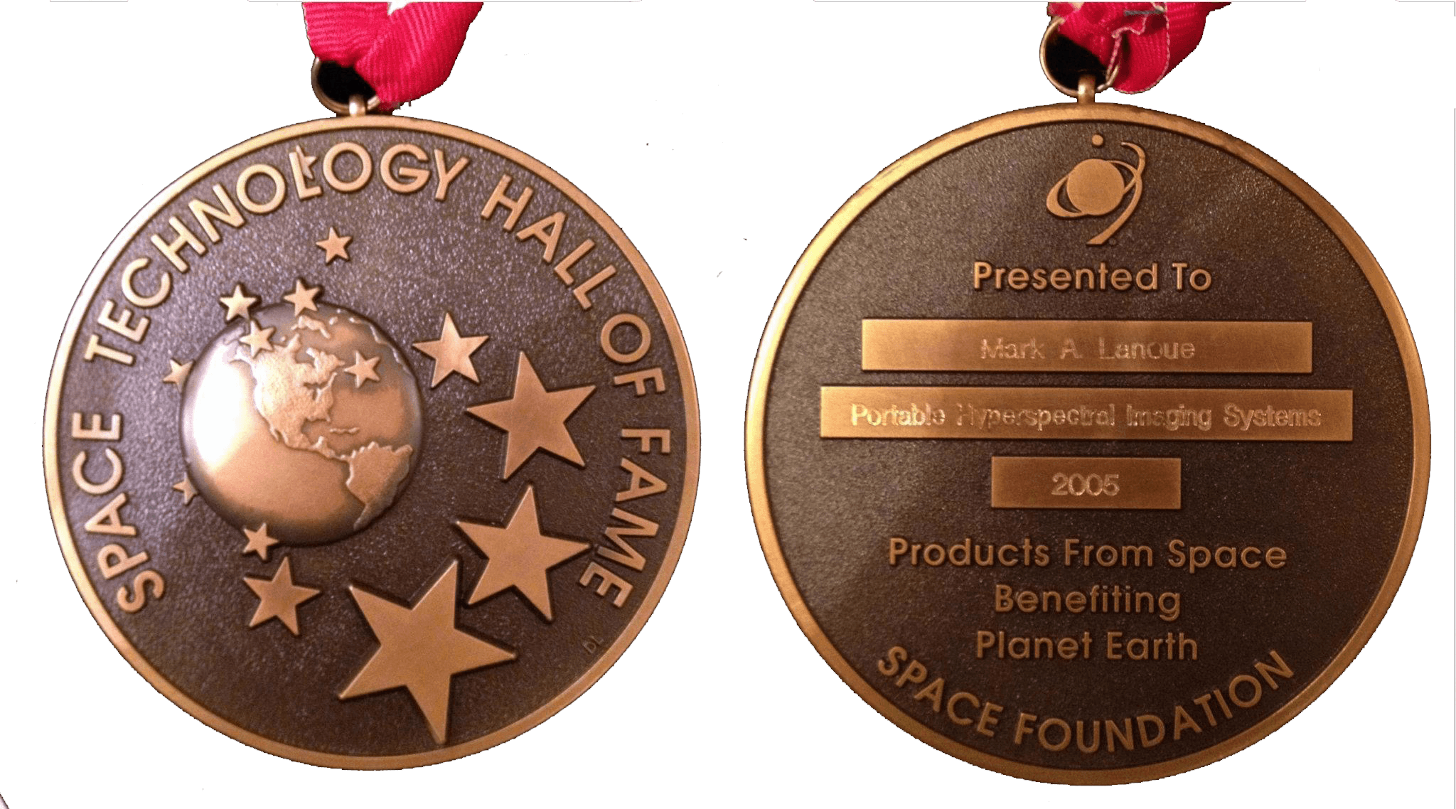 Two medals with space-themed designs and text, one showing a globe and stars, the other with engraved text and logo.