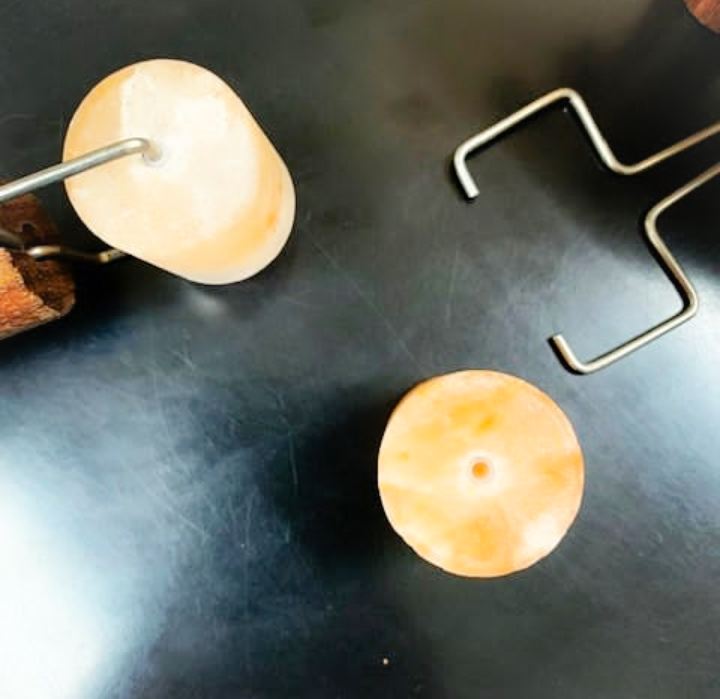 Two round, glowing objects on a dark surface with metal hooks nearby.