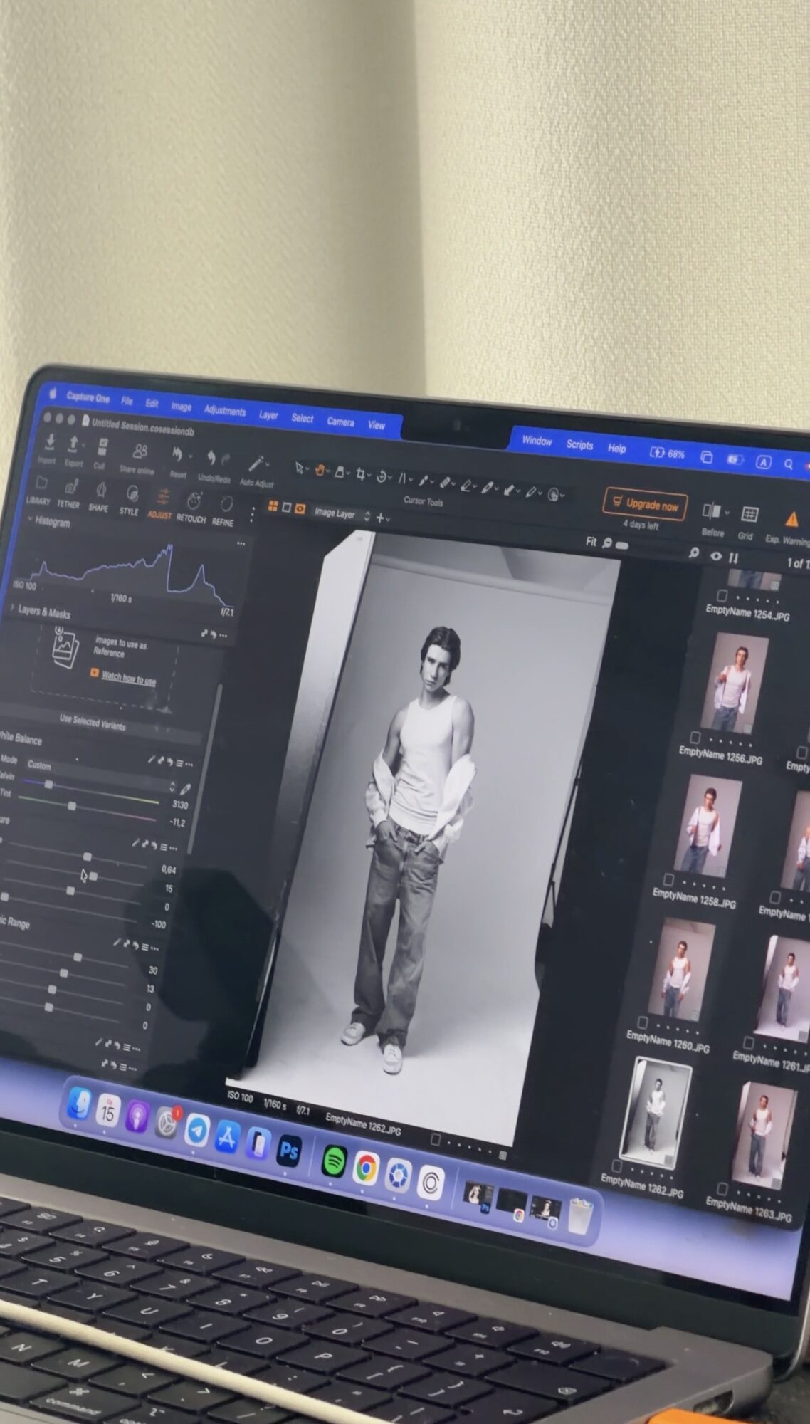 Laptop screen displaying a black-and-white photo of a person standing, with photo editing software open on the screen.