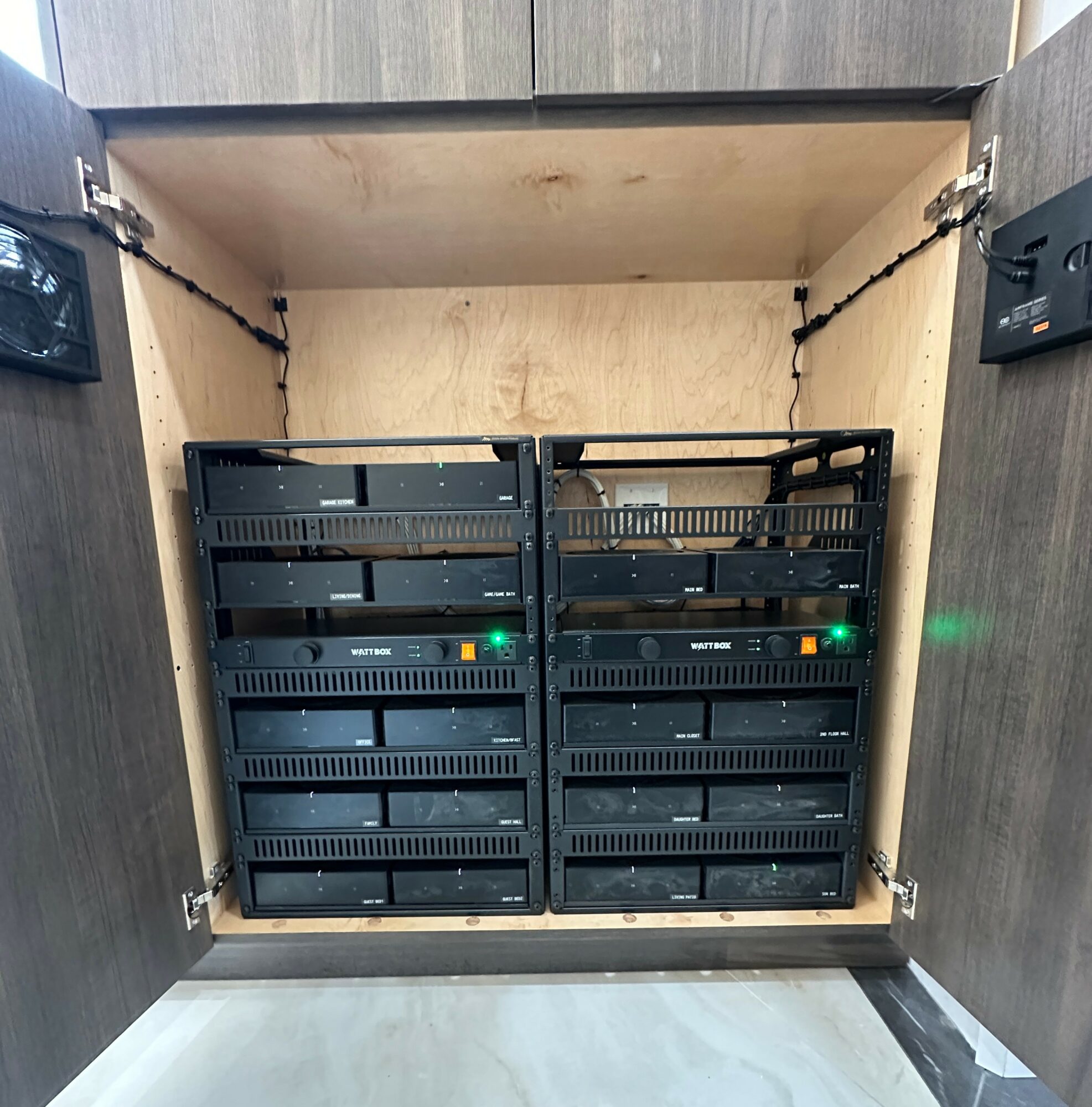 Open cabinet with two server racks inside, green and orange indicator lights visible, mounted on side panels, with wiring at the top.